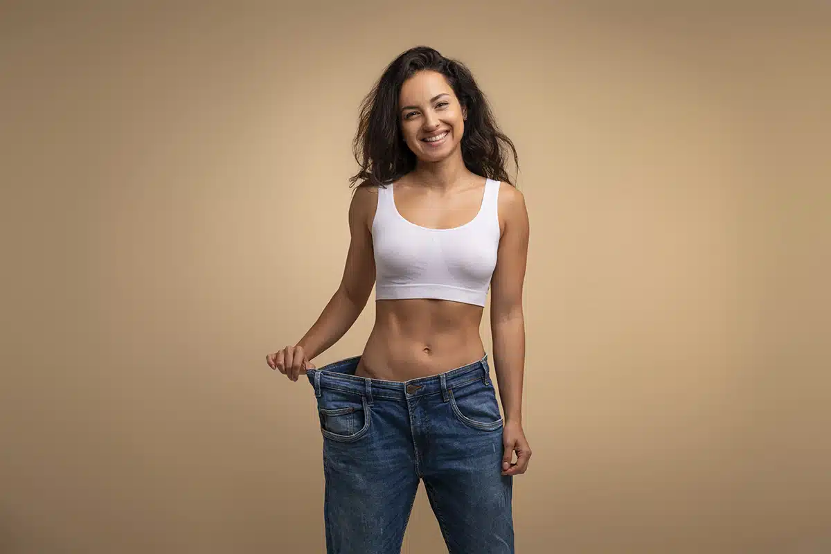 Cheery attractive brunette slender millennial woman wearing huge jeans